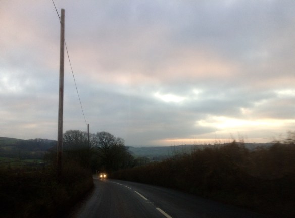 Darkness is falling on wet country roads.
